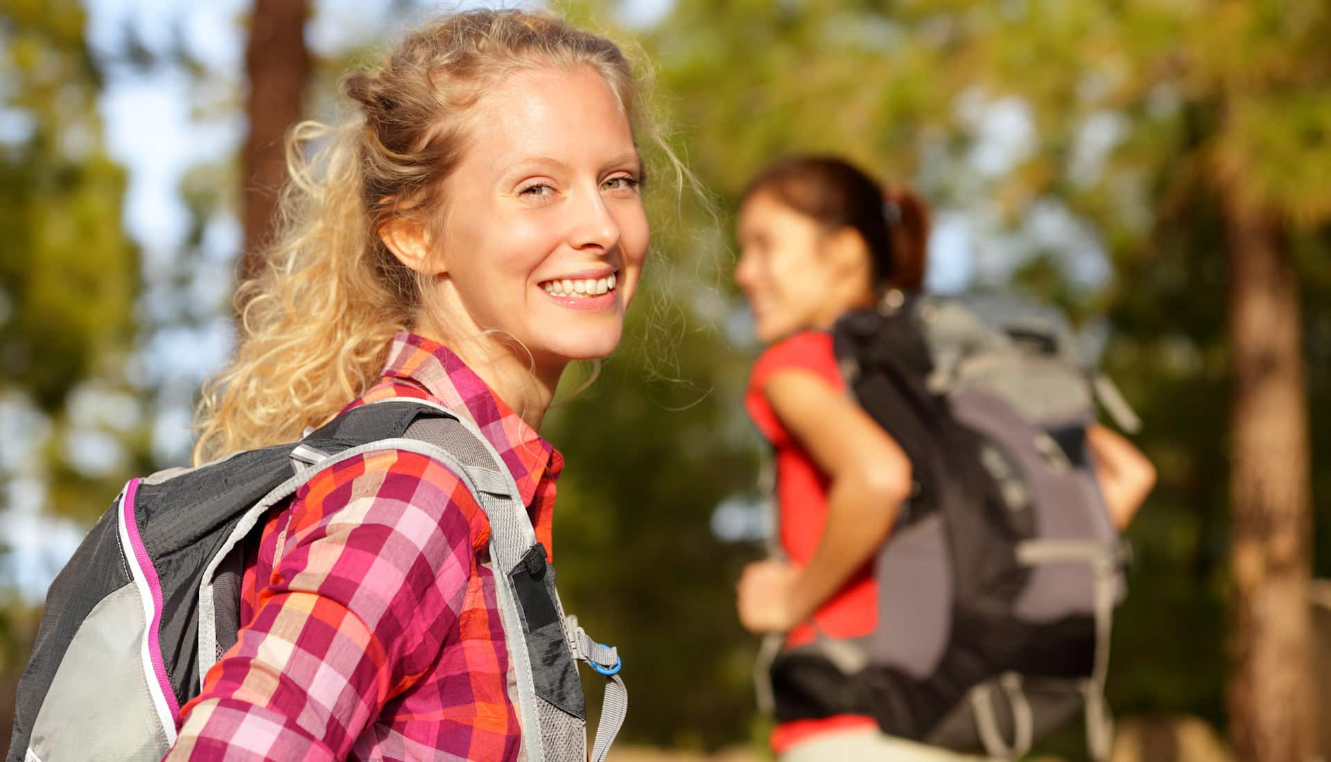 zwei attraktive Frauen wandern lachend im Wald