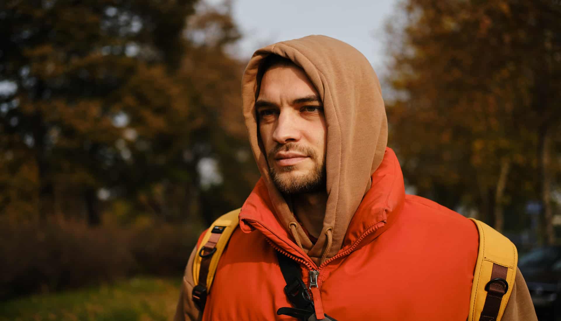 junger Mann mit Hoodie im herbstlichen Wald
